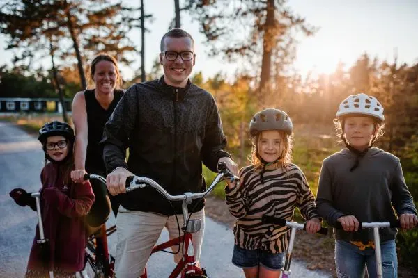 Viisi henkinen perhe on ulkoilemassa potkulaudoin ja pyörällä